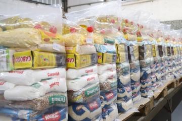 Cestas básicas com arroz, óleo e outros itens empilhadas no galpão