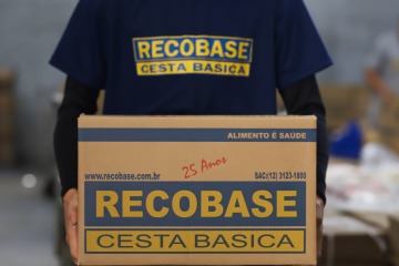 Funcionário segurando uma caixa de cesta básica Recobase